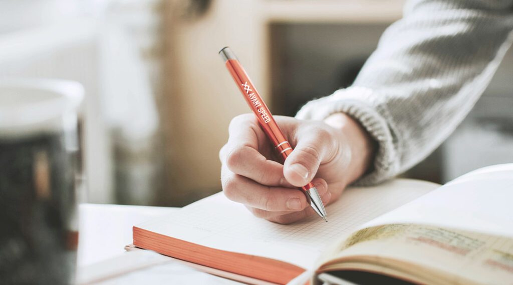 Person writing with a branded pen 