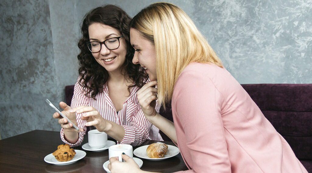 People looking at a phone over coffee