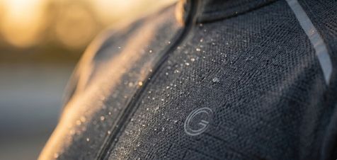 Close-up of a corporate logo printed on the chest of a black high-performance tracksuit