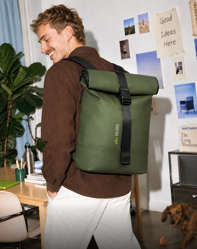Man wearing olive green roll-top laptop backpack with custom printed logo in office
