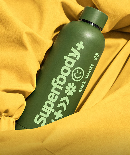Branded olive green reusable thermal water bottle resting on yellow fabric